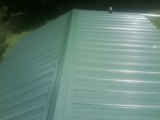 New green metal panels meeting at the ridge of a roof — Flat Roof Repair work by our crew in West Chesterfield