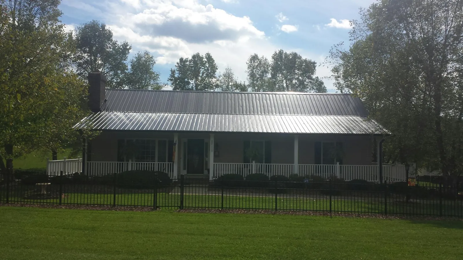 Gray metal roof on a brick ranch with a full width front porch — Gutter Guard Installation work by our crew in West Chesterfield