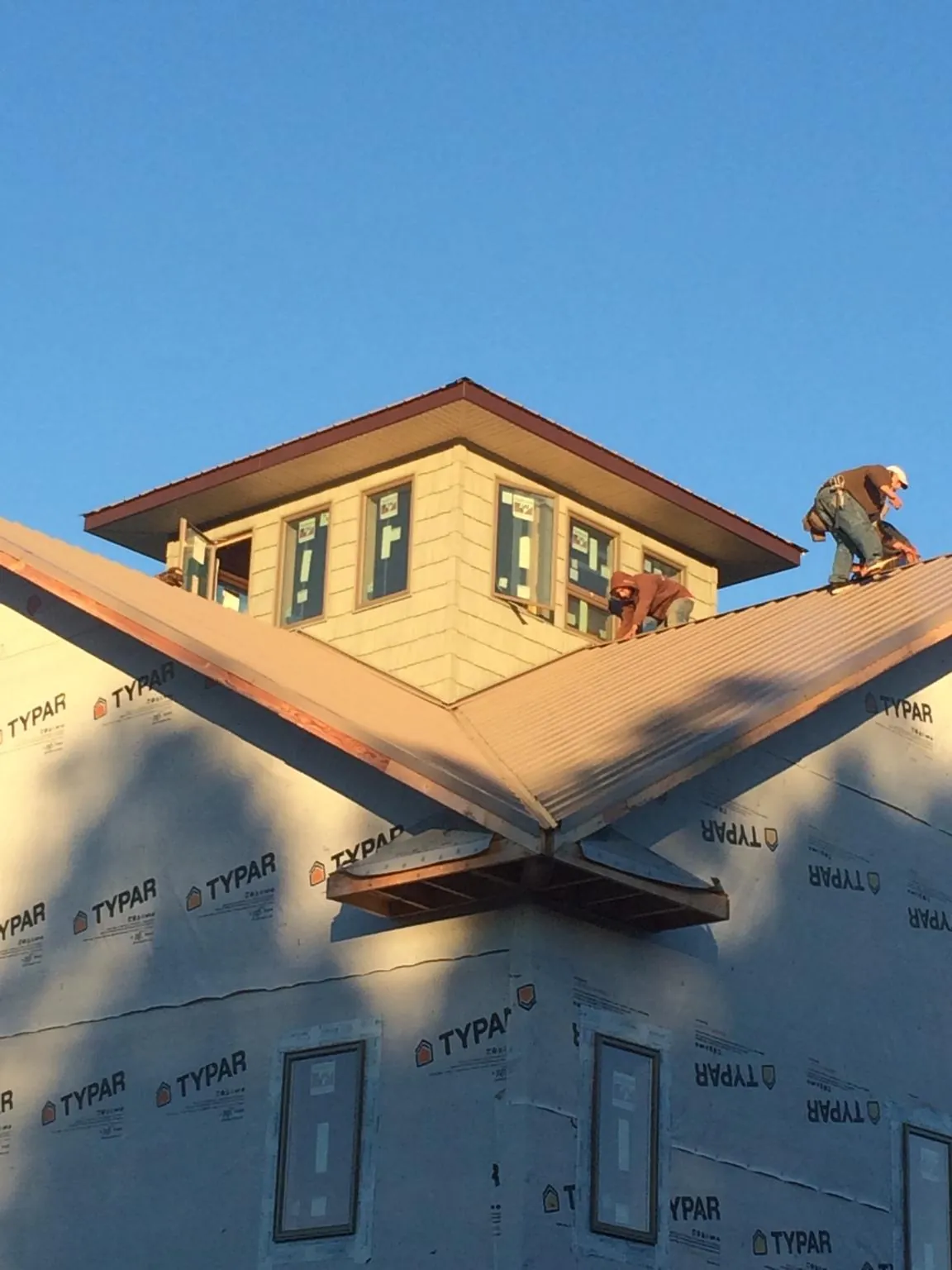Roofers working around a rooftop cupola on a new metal roof at sunset — Roof Waterproofing in West Chesterfield by Roofing Brothers